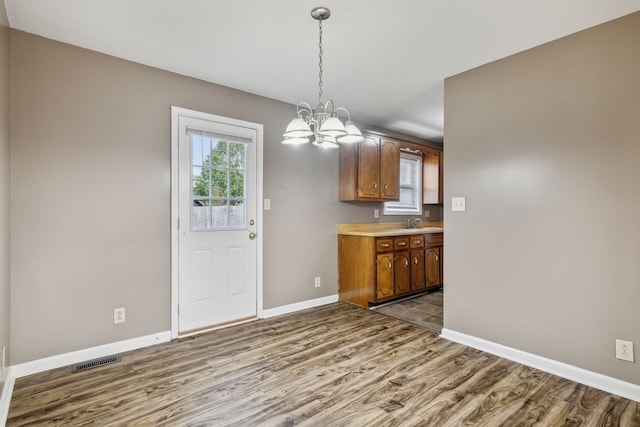 kitchen featuring hardwood / wood-style flooring, decorative light fixtures, sink, and a chandelier