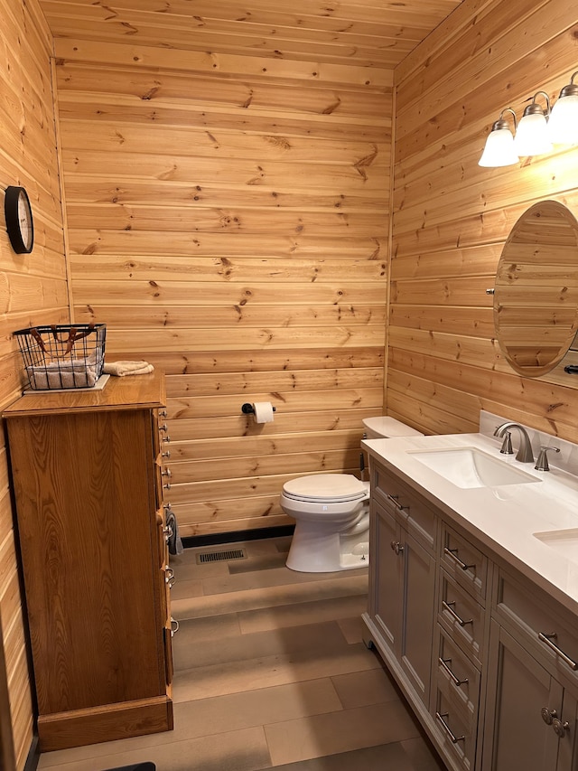 bathroom featuring vanity, toilet, and wood walls