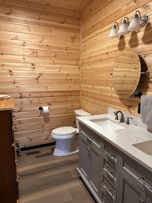 bathroom with vanity, hardwood / wood-style flooring, toilet, and wooden walls