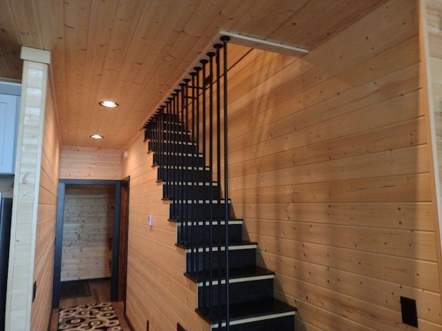 staircase featuring wood ceiling and wood walls