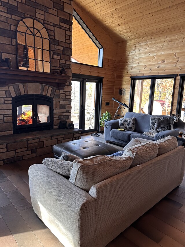 living room with high vaulted ceiling, a stone fireplace, wood ceiling, and wooden walls