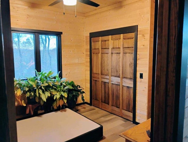 interior space featuring light hardwood / wood-style flooring, ceiling fan, and wood walls