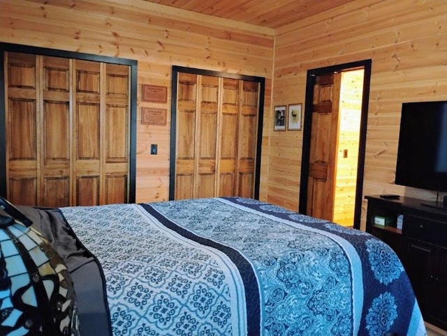 bedroom with wooden ceiling, wooden walls, and two closets