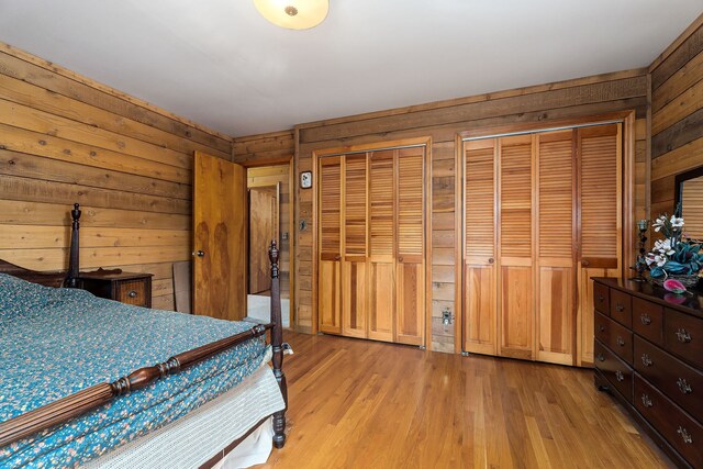 bedroom featuring light hardwood / wood-style floors, multiple closets, and wooden walls