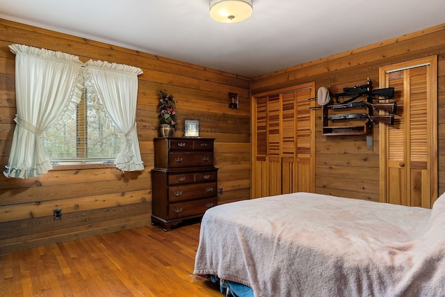 bedroom with hardwood / wood-style floors and wooden walls