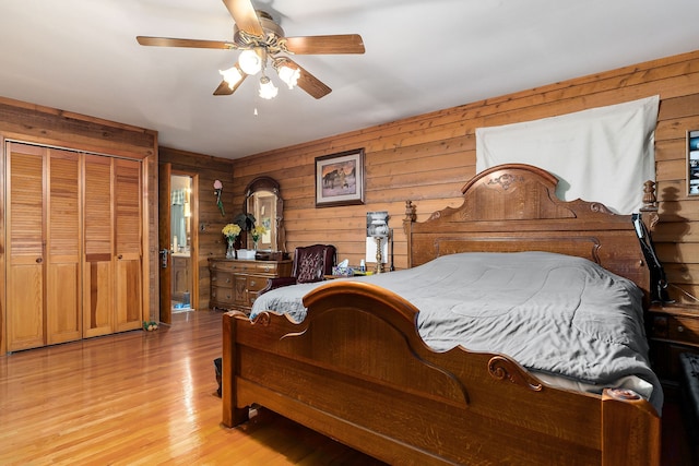 bedroom featuring a closet, light hardwood / wood-style floors, ceiling fan, and wooden walls