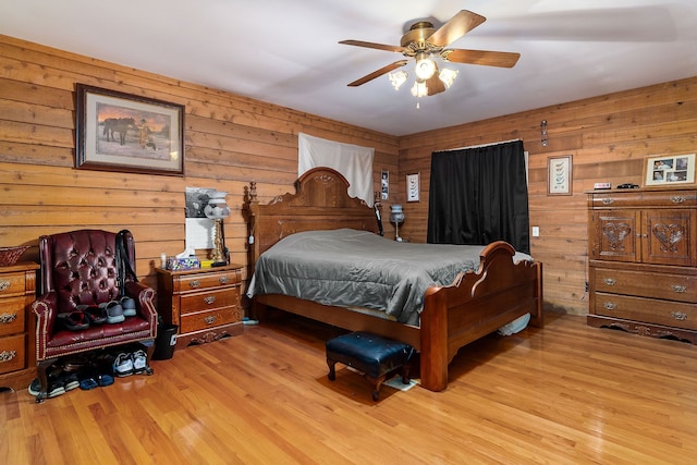 bedroom with light hardwood / wood-style floors, ceiling fan, and wooden walls