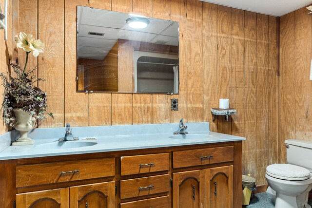 bathroom featuring vanity, toilet, and wood walls