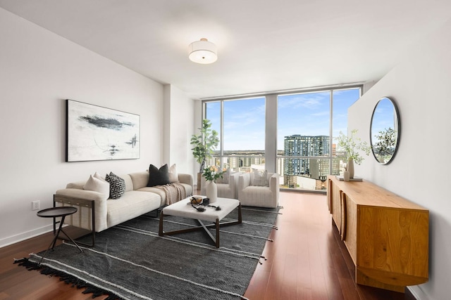 living room with a wealth of natural light, dark hardwood / wood-style flooring, and a wall of windows