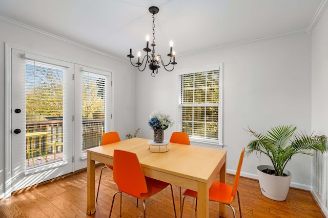 dining area with wood-type flooring, ornamental molding, and an inviting chandelier