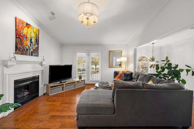 living room featuring hardwood / wood-style flooring, a notable chandelier, ornamental molding, and a tiled fireplace