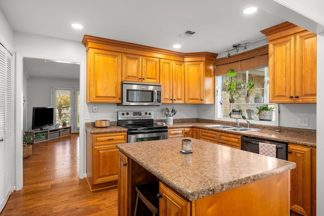 kitchen with hardwood / wood-style floors, a center island, stainless steel appliances, and sink