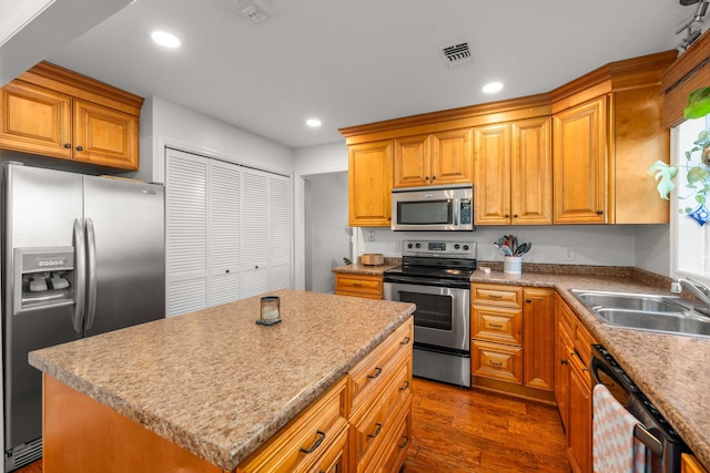 kitchen with a wealth of natural light, sink, dark hardwood / wood-style floors, a kitchen island, and appliances with stainless steel finishes