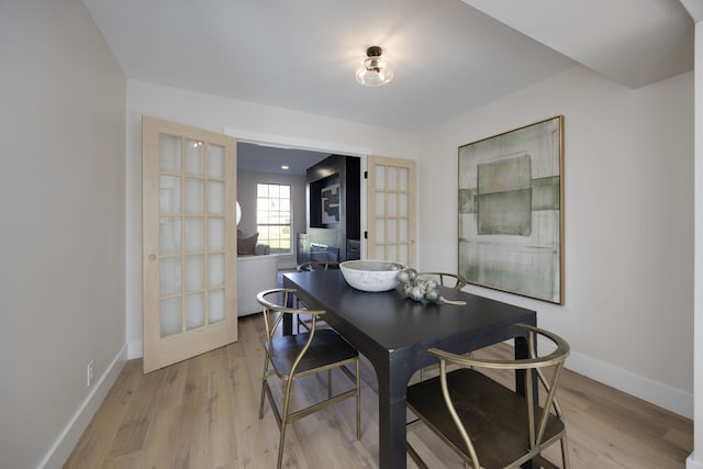 dining area with french doors and light hardwood / wood-style floors