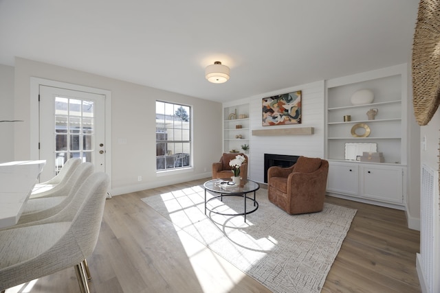 living room featuring a large fireplace, light wood-type flooring, and a wealth of natural light