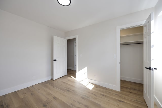 unfurnished bedroom with light hardwood / wood-style flooring and a closet