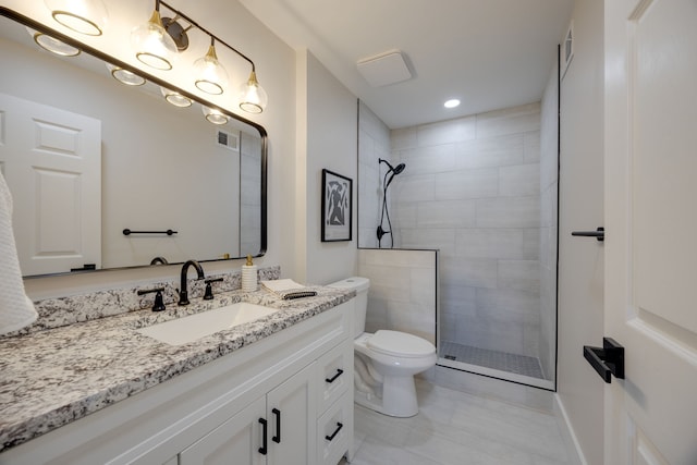 bathroom featuring a tile shower, vanity, and toilet