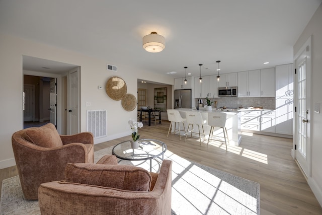 living room with a healthy amount of sunlight, light wood-type flooring, and sink