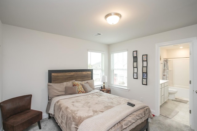 bedroom with light carpet and connected bathroom