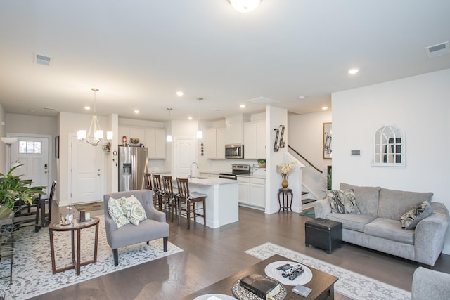 living room with dark hardwood / wood-style floors, an inviting chandelier, and sink