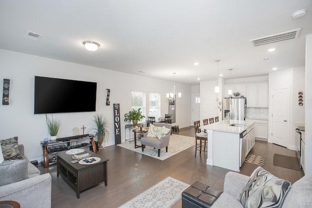 living room with a chandelier and dark wood-type flooring