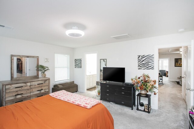 bedroom featuring ensuite bathroom and light carpet