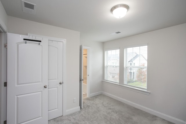 unfurnished bedroom featuring light carpet and a closet