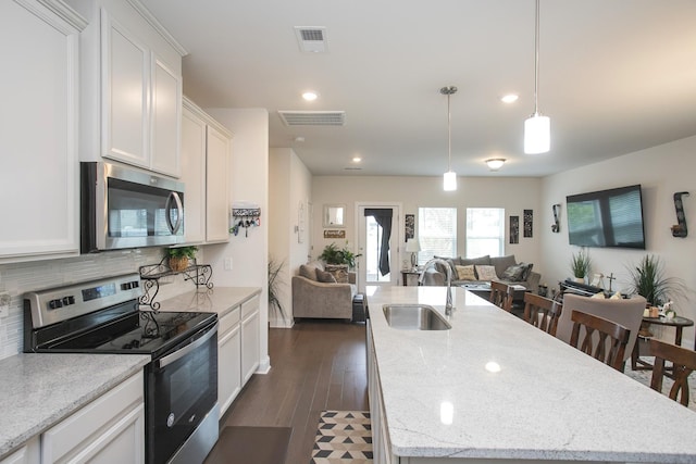 kitchen featuring a center island with sink, a kitchen breakfast bar, sink, dark hardwood / wood-style floors, and appliances with stainless steel finishes