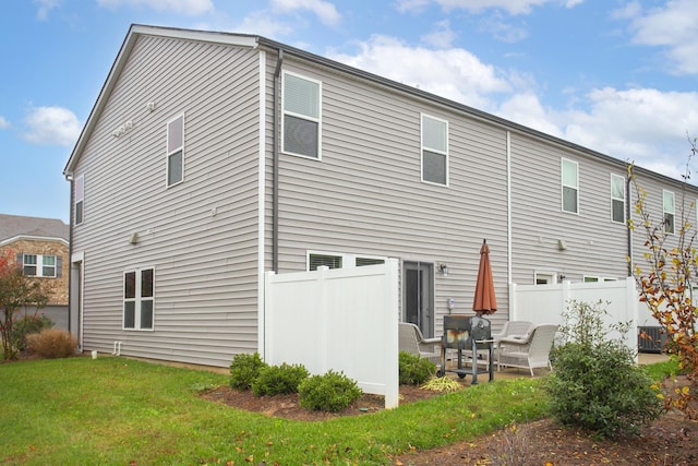 back of property with central AC, a patio area, and a lawn