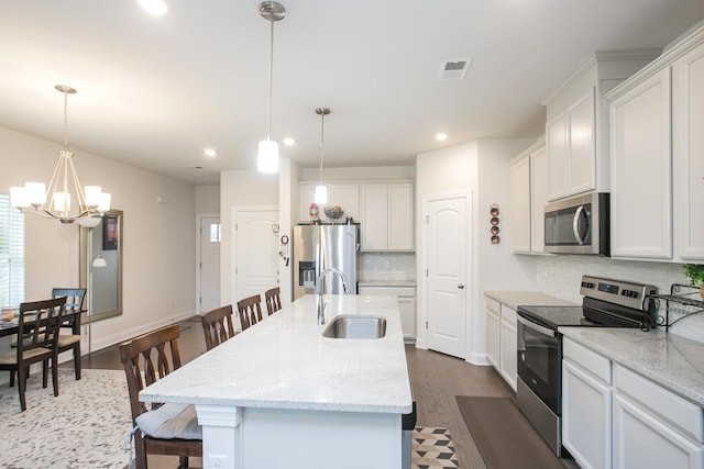 kitchen featuring a kitchen breakfast bar, stainless steel appliances, a center island with sink, and sink