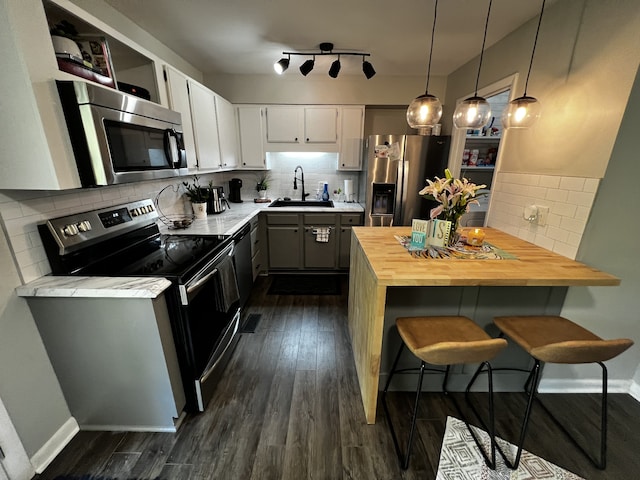 kitchen featuring white cabinetry, sink, decorative light fixtures, decorative backsplash, and appliances with stainless steel finishes