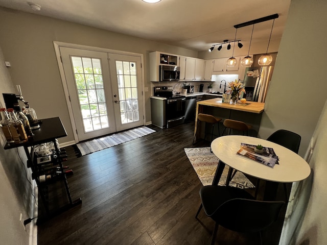 kitchen with french doors, dark hardwood / wood-style floors, appliances with stainless steel finishes, decorative light fixtures, and white cabinetry