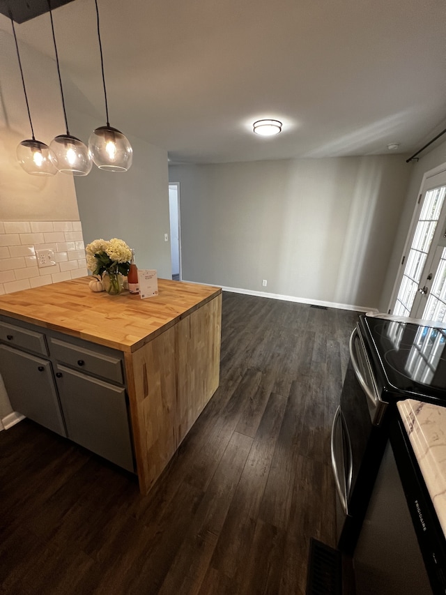 kitchen with hanging light fixtures, wood counters, tasteful backsplash, dark hardwood / wood-style floors, and stainless steel stove