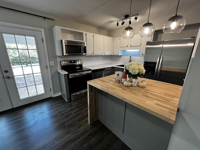 kitchen featuring appliances with stainless steel finishes, tasteful backsplash, white cabinets, dark hardwood / wood-style floors, and hanging light fixtures