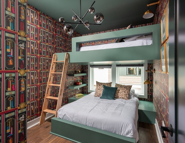 bedroom with wood-type flooring and an inviting chandelier