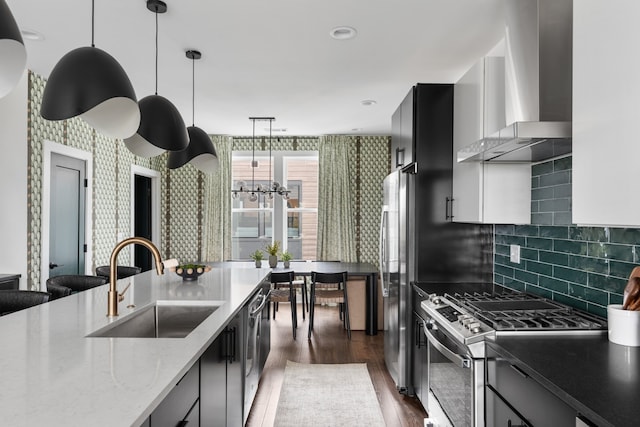 kitchen featuring sink, wall chimney exhaust hood, dark hardwood / wood-style floors, appliances with stainless steel finishes, and light stone counters