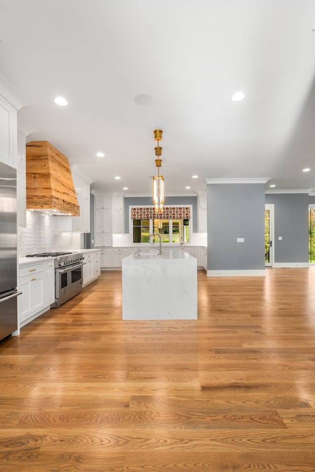 kitchen with custom range hood, high end appliances, decorative light fixtures, light hardwood / wood-style floors, and white cabinetry