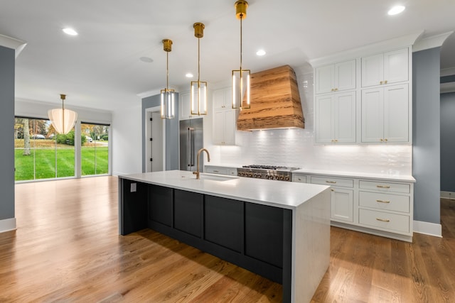 kitchen with sink, hanging light fixtures, light hardwood / wood-style floors, white cabinets, and custom range hood