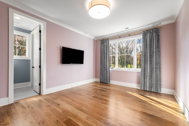 spare room featuring light hardwood / wood-style flooring, a healthy amount of sunlight, and crown molding