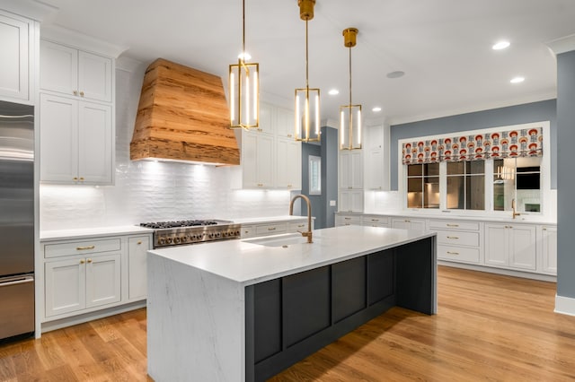 kitchen featuring backsplash, a center island with sink, sink, light hardwood / wood-style flooring, and white cabinetry