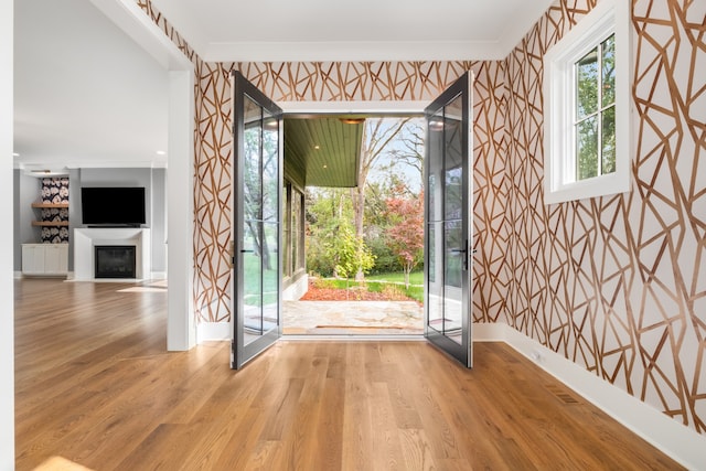 doorway to outside featuring wood-type flooring and crown molding