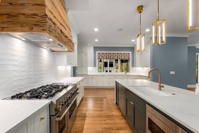 kitchen featuring light stone countertops, sink, stainless steel appliances, hanging light fixtures, and white cabinets