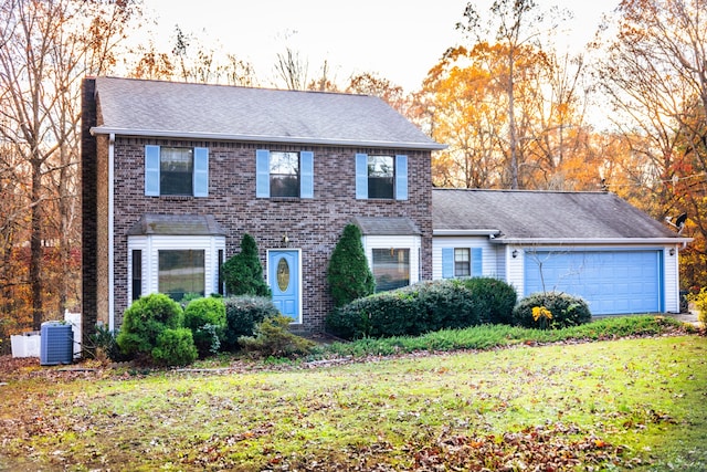 colonial home featuring a front lawn, a garage, and central AC unit