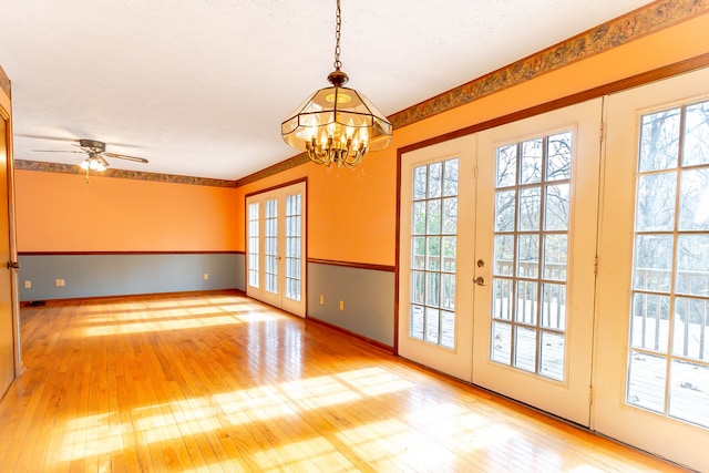 interior space with french doors, ceiling fan with notable chandelier, and hardwood / wood-style flooring