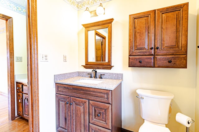 bathroom with hardwood / wood-style flooring, vanity, and toilet