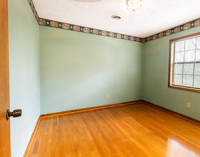 unfurnished room with wood-type flooring and a textured ceiling