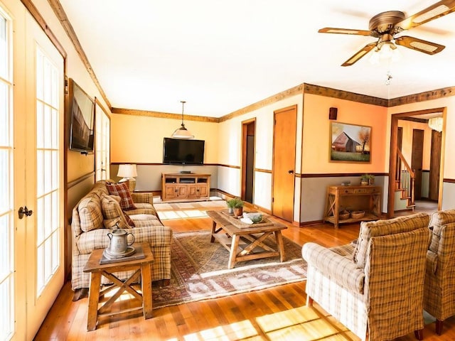 living room featuring ceiling fan, wood-type flooring, and crown molding