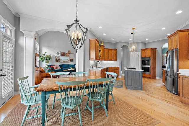 dining room with a notable chandelier, crown molding, sink, and light hardwood / wood-style flooring