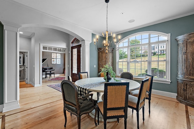 dining room featuring a chandelier, decorative columns, ornamental molding, and light hardwood / wood-style flooring