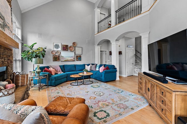 living room featuring a wealth of natural light, a fireplace, high vaulted ceiling, and light wood-type flooring